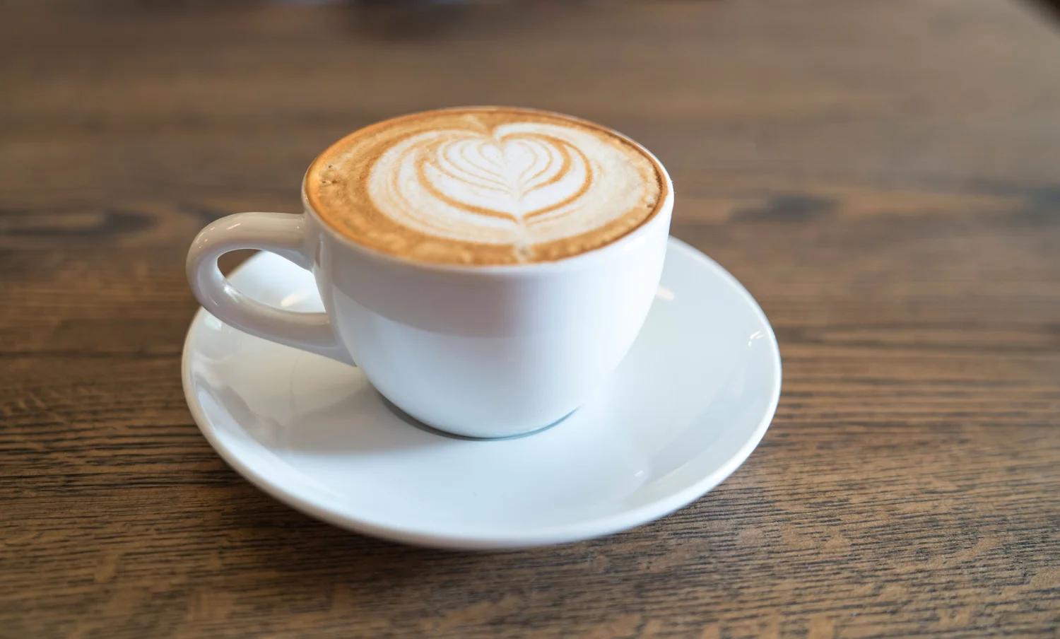 Cappuccino with heart-shaped latte art on a wooden table