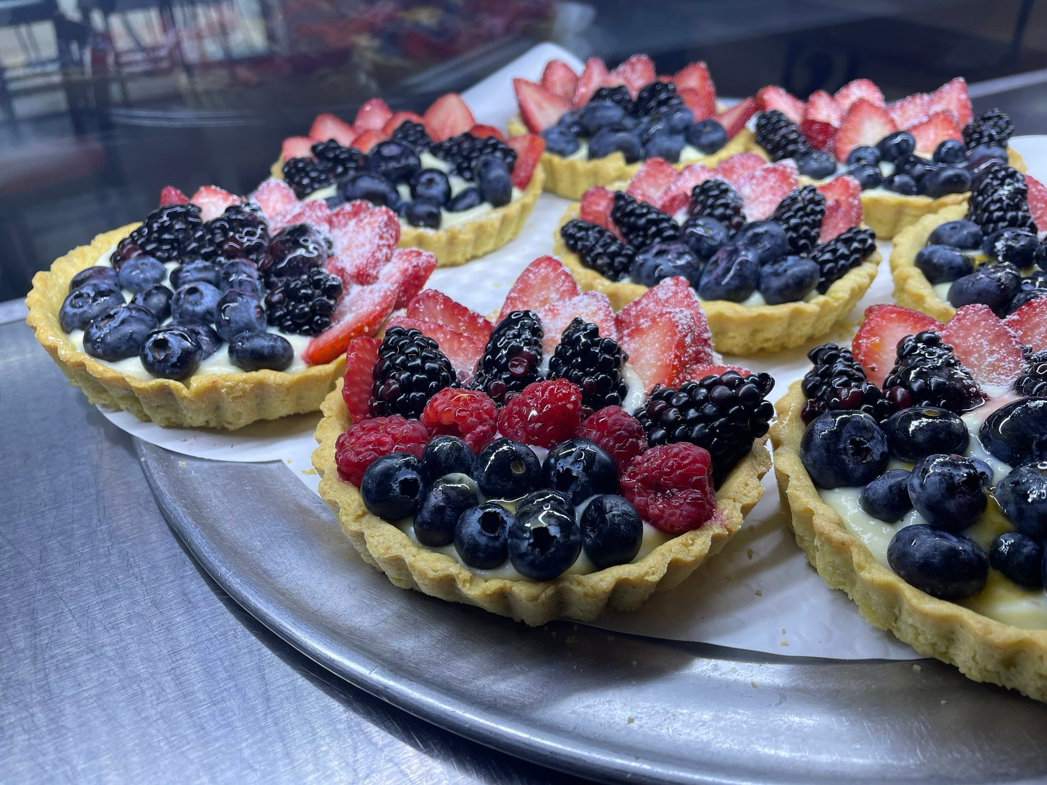 Fresh fruit tarts with berries on a metal tray